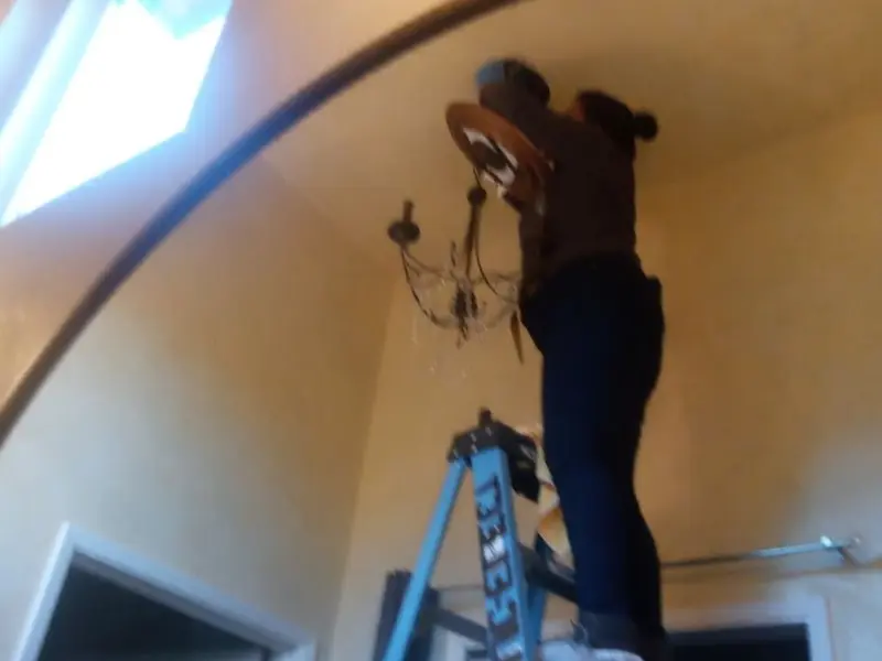 Electrician installing a chandelier in a Portsmouth residence